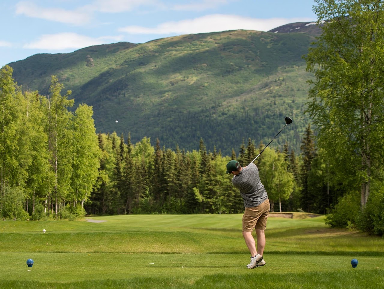Golfer teeing off with Colorado mountain backdrop at Indian Peaks Golf Course